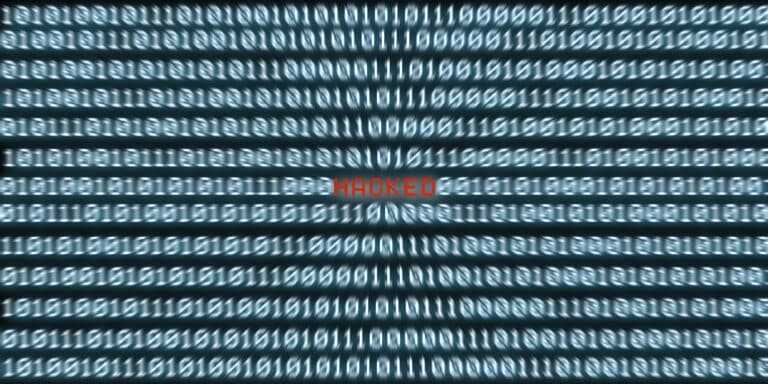 Bildschirmfüllender Binärcode, in der Mitte leuchtet das rote Wort HACKED